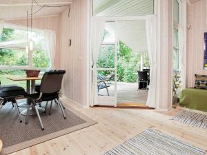 スラーエルセにあるFive-Bedroom Holiday home in Juelsminde 1のテーブルと椅子、ベッドルーム1室が備わります。