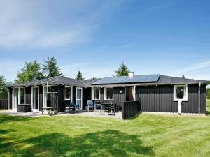 a black house with a lawn in front of it at Five-Bedroom Holiday home in Fjerritslev in Torup Strand