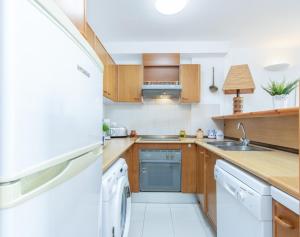 Elle comprend une petite cuisine avec des placards en bois et un réfrigérateur. dans l'établissement Apart-rent Apartamento Port Grec 0161, à Empuriabrava