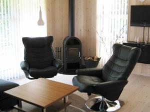 6 person holiday home in Silkeborg في Engesvang: غرفة معيشة مع كرسيين وموقد خشب