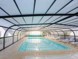 an indoor swimming pool with a glass ceiling at Vacancéole - Résidence Les Terrasses de Pentrez-Plage in Pentrez