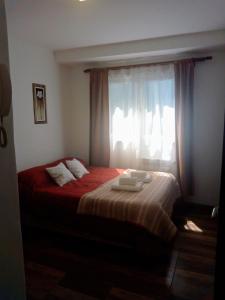 um quarto com uma cama com lençóis vermelhos e uma janela em Astoria Patagonia II habitaciones privadas em San Carlos de Bariloche