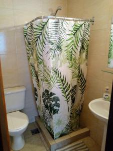 a bathroom with a shower curtain with palm leaves at Astoria Patagonia II habitaciones privadas in San Carlos de Bariloche