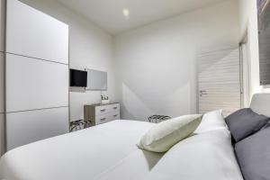 a white bedroom with a white bed and a television at Tourist Apartment Civitavecchia in Civitavecchia