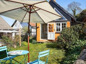 una mesa y sillas con sombrilla frente a una casa en 2 person holiday home in Svaneke-By Traum, en Svaneke