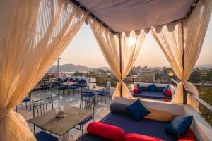 a balcony with a couch and a table and chairs at Shalom Backpackers Udaipur in Udaipur
