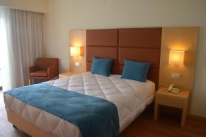 ein Hotelzimmer mit einem großen Bett und einem Stuhl in der Unterkunft Hotel Atlantida Sol in Figueira da Foz