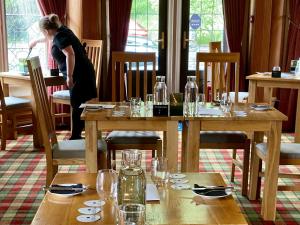 a woman standing in a restaurant with tables with glasses at Knockderry Country House Hotel in Cove