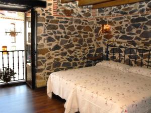 1 dormitorio con 1 cama en una pared de piedra en Hostal Residencia El Mirador del Pedroso, en Barbadillo del Pez
