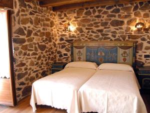 a bedroom with a bed in a stone wall at Hostal Residencia El Mirador del Pedroso in Barbadillo del Pez