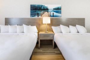 a hotel room with two beds and a table with a lamp at Repotel Aéroport Québec in Quebec City
