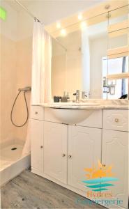 ein weißes Bad mit einem Waschbecken und einer Dusche in der Unterkunft Hyères-plage Studio cabine-L'ayguade BY HC in Hyères
