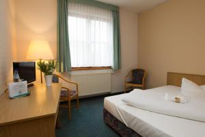 a hotel room with two beds and a desk at Jembo Park Hotel in Jena