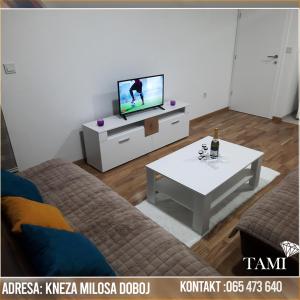 a living room with a tv and a couch and a table at Apartman Tami in Doboj