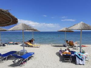 a beach with chairs and umbrellas and the ocean at Hotel Zografos in Paralia Katerinis