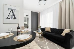 a living room with a black couch and a table at Apartments Wrocław Aleja Architektów by Renters in Wrocław