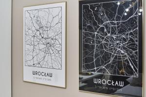 twee ingelijste posters aan een muur met een kaart bij Apartments Wrocław Aleja Architektów by Renters in Wrocław