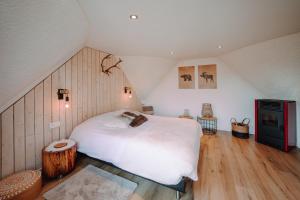 sypialnia z dużym białym łóżkiem na poddaszu w obiekcie Chalet Boréal avec bain à bulles - In the Woods w mieście Gesves