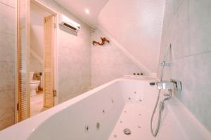 a white bath tub in a bathroom with a toilet at Chalet Boréal avec bain à bulles - In the Woods in Gesves