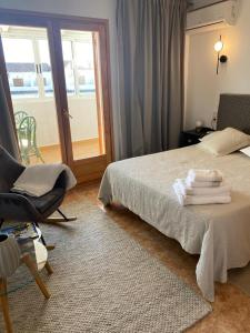 a bedroom with a bed and a chair and a window at Duplex Torre Almadrava in Denia