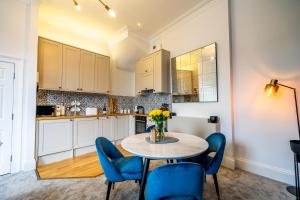 a kitchen with a table and some blue chairs at 5 Rowntree House in York