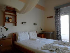a bedroom with a bed with white sheets and a window at PANORAMA in Pitsidia