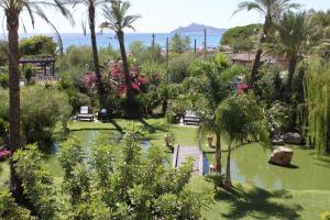 a garden with palm trees and a body of water at Hotel Mediterraneo in Santa Maria Navarrese