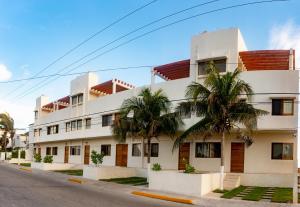 a white building with palm trees in front of it at Villas Najo' Isla Mujeres. in Isla Mujeres