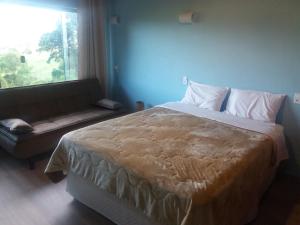 a bedroom with a bed and a couch and a window at Pousada Campestre Sítio da Lua in Camanducaia