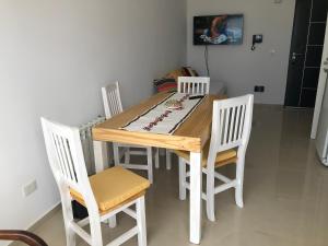 mesa de comedor con 4 sillas blancas en Departamento Centrico VDL en Puerto Madryn