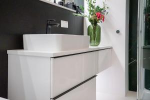 La salle de bains est pourvue d'un lavabo blanc et d'un vase fleuri. dans l'établissement Granatowy Apartament, à Grodzisk Mazowiecki