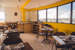 a restaurant with yellow walls and tables and windows at Guará Inn Flat Service in Guaratinguetá