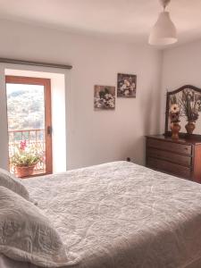 um quarto com uma cama, uma cómoda e uma janela em Casa Sambinho Gerês em Rio Caldo