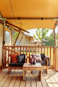 a patio with a couch and a table on a deck at Frei wie der Wind-Glamping in Dierhagen