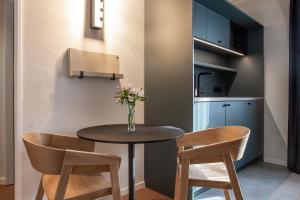 a small dining room table with two chairs and a vase of flowers at B-Hotel in Düsseldorf