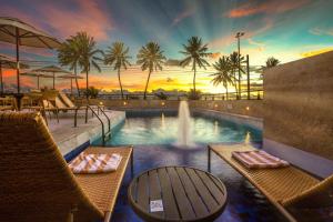 uma piscina com cadeiras e uma fonte com um pôr-do-sol em Hardman Praia Hotel em João Pessoa