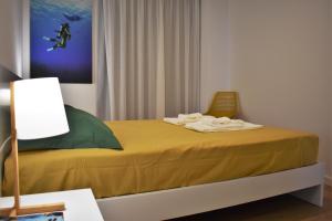 ポンタ・デルガダにあるOcean Blue Apartmentのベッドルーム1室(黄色いシーツとランプ付きのベッド1台付)