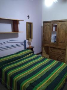 サンタ・ロサ・デ・カラムチタにあるCabañas La Pircaのベッドルーム1室(緑と黄色のストライプ毛布付きのベッド1台付)