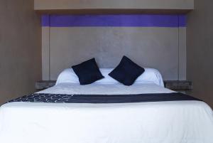 a large white bed with two black pillows on it at Hotel Platino in Monterrey
