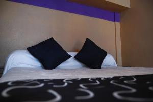 a bed with black and white pillows on it at Hotel Platino in Monterrey