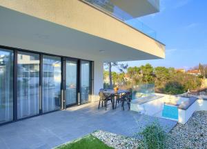 un patio al aire libre con mesa, sillas y puertas de cristal en Apartments Perle, en Malinska