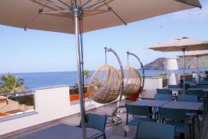 een restaurant met tafels en stoelen en uitzicht op de oceaan bij Hotel Por Do Sol in Tarrafal