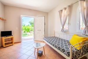 a room with a bed and a tv and a window at Alavastros Maisonettes Near 3 sandy beaches in Vasilikos