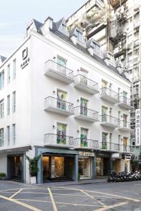 a white building with balconies on a street at Dandy Hotel - Tianjin Branch in Taipei