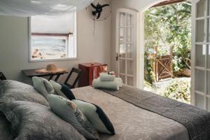 two beds in a room with a view of the ocean at Bonito Paraiso Ilha Grande in Abraão