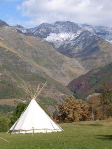 un tipi blanc dans un champ avec des montagnes en arrière-plan dans l'établissement Tipi nature grand confort, à Gavarnie