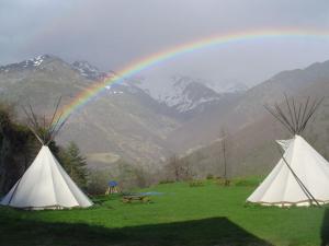 two white tents in a field with a rainbow at Tipi nature grand confort in Gavarnie