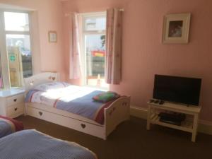 Postel nebo postele na pokoji v ubytování PINK HOUSE ,Opposite Beach ,SLEEPS 6 , 2 BEDROOM GROUND FLOOR SELF CONTAINED GARDEN FLAT , PRIVATE ENTRANCE , KITCHEN , Guaranteed Parking ,Wifi , Movies ,Bathroom ,fridge , microwave ,BEDROOM 1, DOUBLE BED & 2 SINGLE BEDS ,BEDROOM 2 , DOUBLE BED