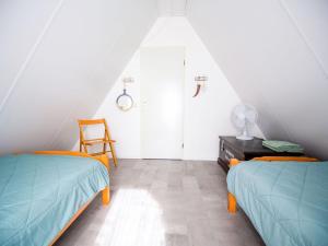 um quarto no sótão com 2 camas e uma cadeira em Modern Holiday Home in Friesland by the Lake em Anjum