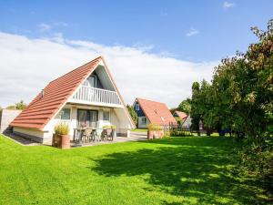 uma casa com um telhado inclinado num relvado verde em Modern Holiday Home in Friesland by the Lake em Anjum